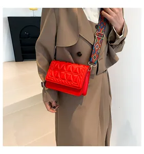 Detail of red quilted crossbody bag featuring a colorful woven geometric strap
