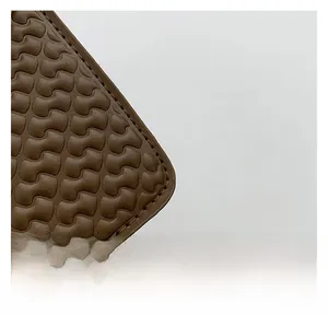 Detail of brown embossed wave texture and precision stitching on a leather handbag