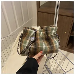 Detail of wool plaid bucket bag with silver metal ball charm and chain strap