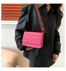 Close-up of pink quilted crossbody bag with colorful ethnic patterned wide strap