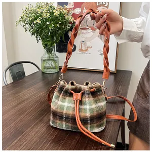 Detail of wool bucket bag with plaid pattern on wood table with floral background