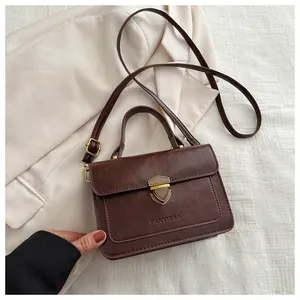 Detail of dark brown PU leather crossbody bag with a vintage gold shield lock and handle
