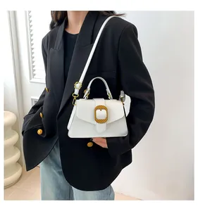 Detail of white leather trapezoid handbag with textured gold buckle and handle