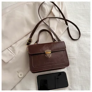Detail of vintage brown crossbody bag with a metallic shield lock and branded hardware