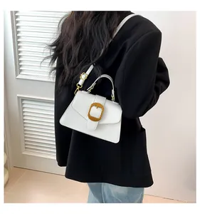 Close-up of a white leather bag with a gold metal buckle on a woman's shoulder