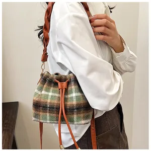 Detail view of plaid wool bucket bag featuring woven strap and drawstring closure