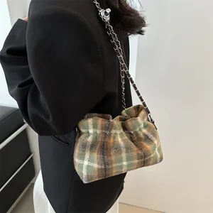 Fashionable green plaid wool bucket bag with silver chain strap worn by a female model