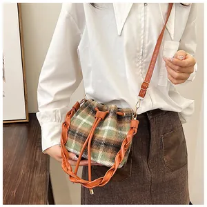 Detail of checkered wool bucket bag with drawstring closure and braided leather handle