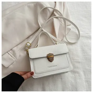 Close-up of white leather square bag featuring a gold shield-shaped lock and logo