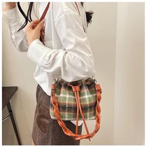 Detail of checkered wool bucket bag featuring leather drawstring and woven handle