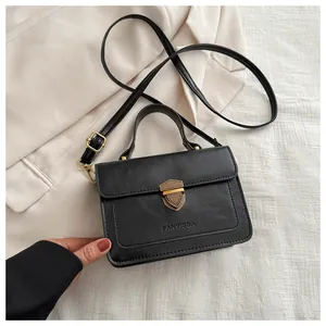 Detail of the black leather textured crossbody bag with a golden shield lock and logo