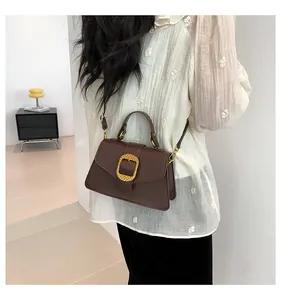 Detail of dark brown retro shoulder bag with gold metal buckle and leather handle strap