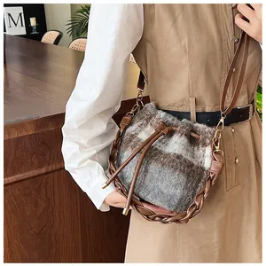 Detail of wool bucket bag with retro plaid pattern and brown leather braided handle