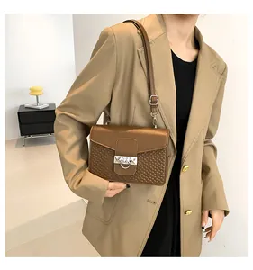 Brown leather crossbody bag with rhombic pattern and silver metal lock on a model