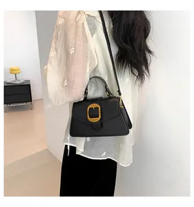Close-up of black leather crossbody bag with golden woven texture square buckle