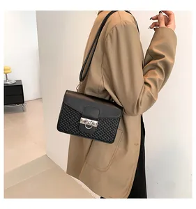 Detail of black crossbody bag with woven texture and silver metal ring buckle on model