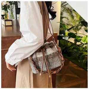 Detail of wool bucket bag with plaid pattern, brown braided handle, and drawstring closure