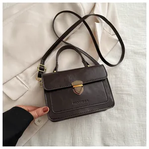 Detail of vintage dark brown crossbody bag with gold shield lock and embossed logo