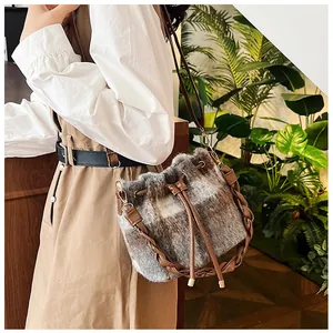 Detail of wool bucket bag with plaid pattern, drawstring closure and woven leather handle
