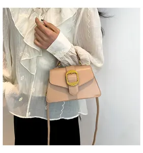Detail of a beige fashion crossbody bag featuring a large textured gold circular buckle