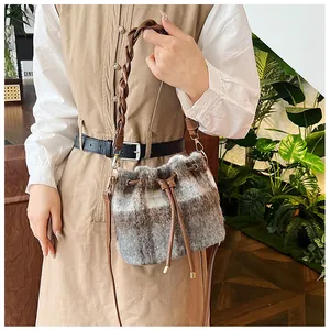 Detail of wool plaid bucket bag with brown woven leather handle and gold hardware