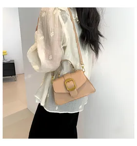 Detail view of a beige leather shoulder bag with a gold square buckle and fine textures