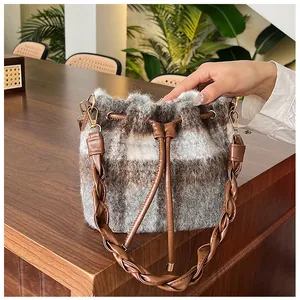 Detail view of the woolen plaid bucket bag with woven handle and brown leather drawstring