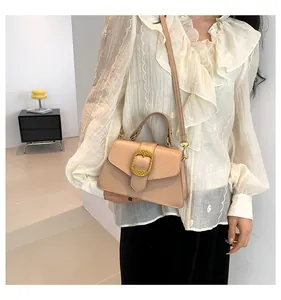 Chic beige crossbody bag with textured gold buckle detail shown on a female model