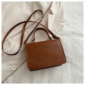 Top view of vintage brown PU leather handbag with gold lock and textured blazer background
