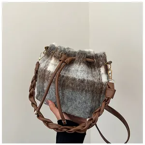 Detail of wool bucket bag showing brown plaid texture and leather drawstring closure