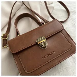 Close-up of vintage brown PU crossbody bag featuring a golden shield lock and top handle
