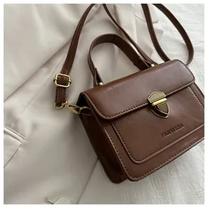 Detail of vintage brown leather crossbody bag with shield-shaped gold clasp and handle