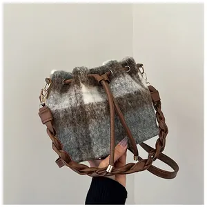Detail of wool bucket bag showing brown plaid texture and woven leather strap