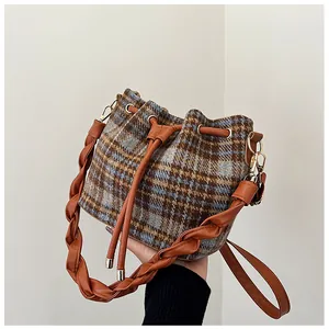 Detail of checkered wool bucket bag featuring leather drawstring and woven handle