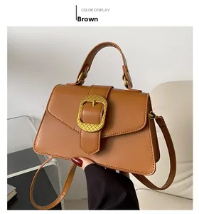 Detailed view of brown handbag with gold woven buckle and polished leather texture