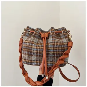 Detailed shot of retro plaid wool bucket bag with twisted leather handle and drawstring closure