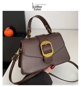 Close-up of coffee brown leather bag with golden grid buckle and top handle details