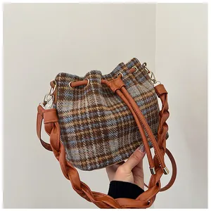 Detail of vintage plaid wool bucket bag with drawstring closure and woven handle