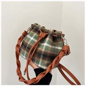 Detail of green checkered wool bucket bag featuring braided shoulder strap and leather drawstring