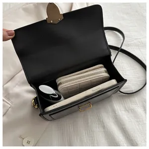 Top view of black leather crossbody bag interior showing spacious storage with gold lock