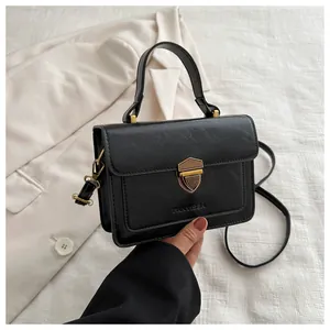 Close-up of black retro square handbag with gold shield clasp and branded logo detail