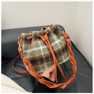 Detail of checkered wool bucket bag featuring woven handle and caramel leather drawstring