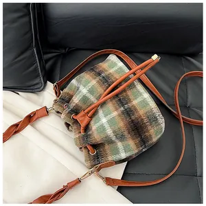 Detail of checkered wool bucket bag with drawstring closure and brown leather shoulder strap