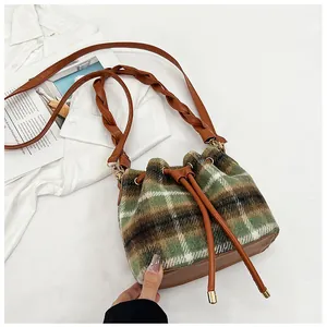 Detail of plaid wool bucket bag with leather drawstring and woven shoulder strap