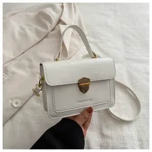 Detail of white leather small square bag with gold metal clasp and logo branding