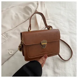 Macro view of a brown vintage leather bag showing metal shield lock and brand engraving