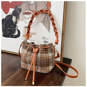 Detailed close-up of retro plaid drawstring bucket bag on a vintage wooden table surface