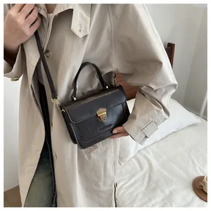 Detail of a dark brown vintage crossbody bag featuring a golden shield lock and top handle