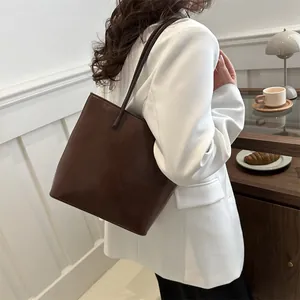 Minimalist deep brown leather tote bag for women showing trapezoid silhouette on white suit
