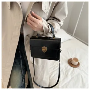 Close-up of vintage black crossbody bag with golden shield lock and fine leather texture